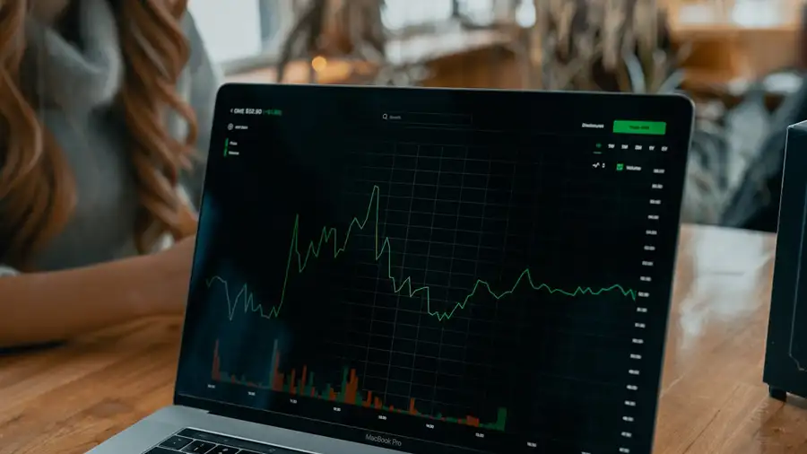 A laptop on a table showing a falling price chart